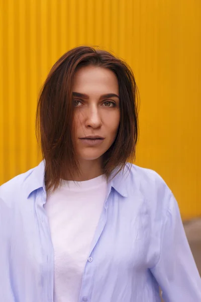 Retrato mulher atraente no fundo amarelo. Ela olha para a câmera pretensiosa ou arrogante. Menina morena com cabelo curto . — Fotografia de Stock