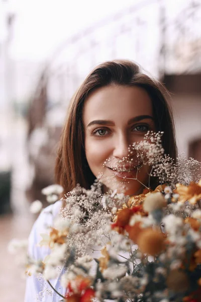 Retrato de mujer hermosa que disfruta de las flores. Ramo de flores de campos — Foto de Stock