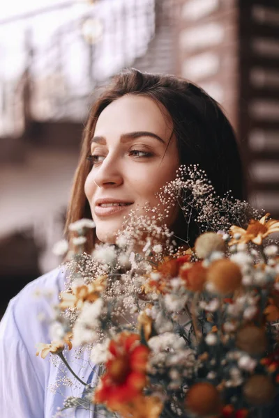 Retrato de mujer hermosa que disfruta de las flores. Ramo de flores de campos — Foto de Stock