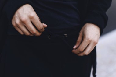Þeridi üzerinde spor pantolon bağlayan adam. Siyah spor takım elbise giyen adam. Giyim detayları. 