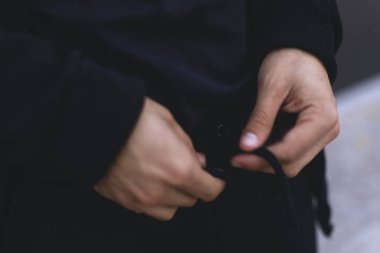 Þeridi üzerinde spor pantolon bağlayan adam. Siyah spor takım elbise giyen adam. Giyim detayları. 