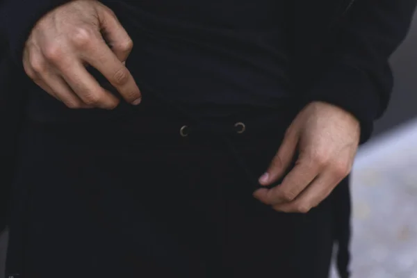 Мужчина завязывает кружева на спортивных брюках. Человек в черном спортивном костюме. Детали одежды . — стоковое фото