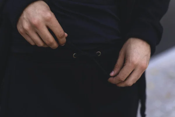 Man knyta spetsar på sport byxor. Mannen bär svart sport kostym. Kläder Detaljer. — Stockfoto