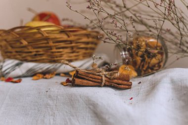 Sicim içinde sarılı tarçın ile natürmort, bir sepet elma bir çizgili keten kumaş, ceviz ve çiçek taç yaprakları üzerinde dur. Sonbahar ya da kış ev rahatlığında kavramı.