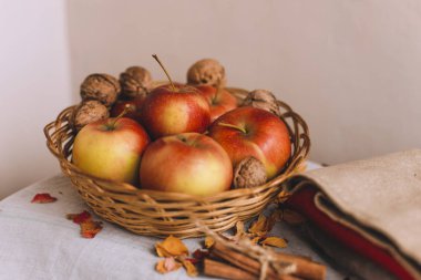 Elma bir hasır sepet, bez, ceviz, çiçek yaprakları ve sicim içinde sarılı tarçın ile natürmort. Sonbahar ya da kış ev konfor kavramını.