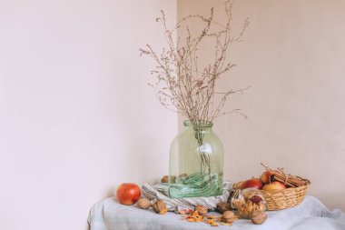 Sicim içinde sarılı tarçın ile natürmort, bir sepet elma bir çizgili keten kumaş, ceviz ve çiçek taç yaprakları üzerinde dur. Sonbahar ya da kış ev rahatlığında kavramı.