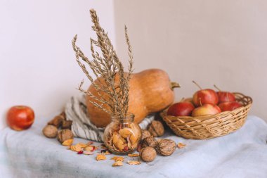 Natürmort tarçın ile elma bankada bir hasır sepet stand, ceviz ve çiçek yaprakları sicim, üzerine çizgili keten kumaş, kabak sarılı. Sonbahar ya da kış ev rahatlığında kavramı. 