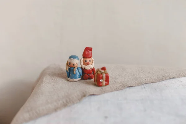 新しい年、サンタ クロース (父フロスト) と雪の乙女、クリスマス カード。織物リネン表面に粘土の置物。フォーカス ギフトから前景 — ストック写真