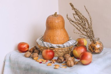Natürmort tarçın ile sarılmış sicim, elma, çizgili bir keten kumaş, ceviz ve çiçek yaprakları bankada bir hasır sepet stand kabak. Sonbahar veya wint ev rahatlığında kavramı