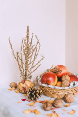 Natürmort tarçın ile sarılmış sicim, koni, çizgili bir keten kumaş, ceviz ve çiçek yaprakları bankada bir hasır sepet stand elma. Sonbahar ya da kış ev rahatlığında kavramı.