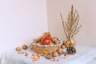 Natürmort tarçın ile sarılmış sicim, koni, çizgili bir keten kumaş, ceviz ve çiçek yaprakları bankada bir hasır sepet stand elma. Sonbahar ya da kış ev rahatlığında kavramı.