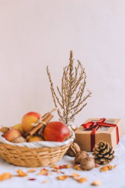 Natürmort tarçın ile sarılmış sicim, koni, çizgili bir keten kumaş, ceviz ve çiçek yaprakları bankada bir hasır sepet stand elma. Sonbahar ya da kış ev rahatlığında kavramı.