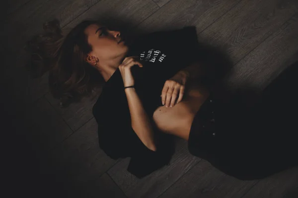 매력적인 섹시 한 여자는 바닥에 놓여 있습니다. 그녀는 관 능을 보인다. 뜨거운 여 자가 착용 총 검은 보기. — 스톡 사진