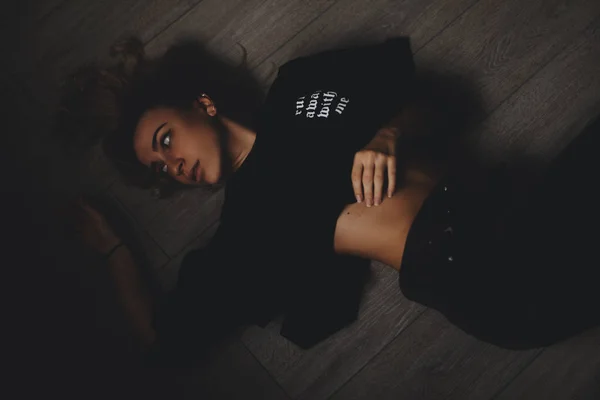 有吸引力的性感的女人躺在地板上。她看起来很性感。辣妹穿完全黑色的样子. — 图库照片