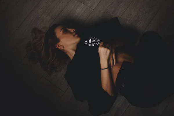 Atractiva mujer sexy yace en el suelo. Parece sensualidad. Chica caliente lleva aspecto negro total . —  Fotos de Stock