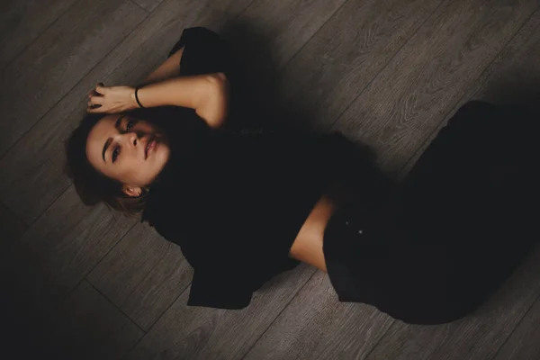 Attraente donna sexy si trova sul pavimento. Sembra sensuale. Ragazza calda indossa total look nero . — Foto Stock