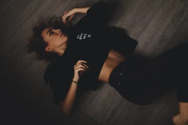 Attraktive sexy Frau liegt auf dem Boden. sie sieht sinnlich aus. hot girl trägt total black look. — Stockfoto