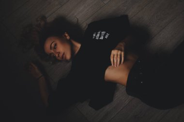 Çekici seksi kadın yerde yatıyor. Duygusallık bakıyor. Sıcak kız toplam siyah bir görünüme giyer.