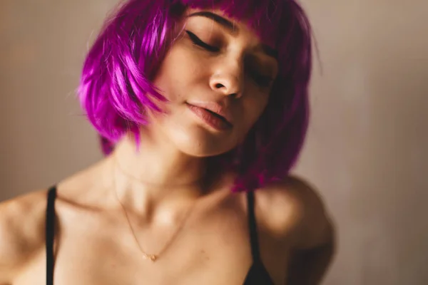 Nahaufnahme Porträt einer jungen Frau mit rosafarbenem Bob-Schnitt und stylischem Make-up. sie sieht glücklich, lächelnd und sexy aus Stockbild
