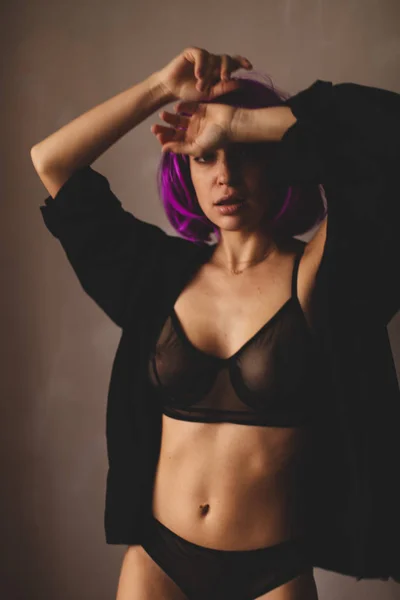 Ragazza attraente indossare parrucca rosa e lingerie nera, camicia. Le donne chiudono una camicia nera. Sexy ragazza decollare o mettere su camicia nera . — Foto Stock