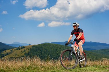 Profesyonel sporcu bisikletçi spor giyim ve güneşli yaz günü, aktif yaşam tarzı ve aşırı spor kavramı üzerinde güzel Karpat Dağları manzarasına tadını çıkarırken yüksek çim Bisiklet Bisiklet kask