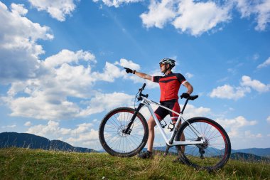 Spor giyim ve çapraz ülke bisiklet üstünde tepe-in tepe ile ayakta ve yaz güneşli gün, aktif yaşam tarzı ve açık spor kavramı blue sky adlı işaret kask profesyonel erkek bisikletçi 