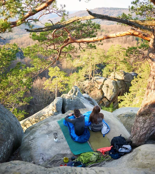 Uyku tulumları büyük kayanın üzerine oturmuş ve zevk huzurlu sabah dağlar, turizm ve aktif yaşam tarzı kavramı genç turist çiftin yukarıdan arkadan görünüm