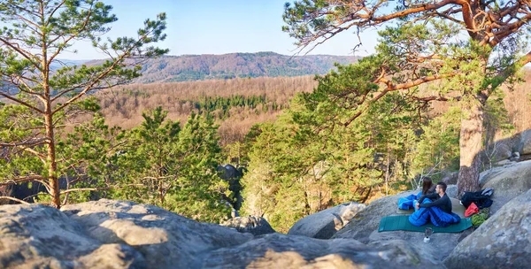 Uyku tulumları büyük kayanın üzerine oturmuş ve dağların muhteşem huzurlu manzarayı genç turist çift erken sabahı, aktif yaşam tarzı kavramı ormanıyla kaplı  