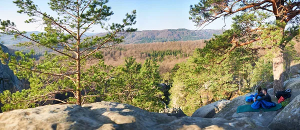 Uyku tulumları büyük kayanın üzerine oturmuş ve dağların muhteşem huzurlu manzarayı genç turist çift erken sabahı, aktif yaşam tarzı kavramı ormanıyla kaplı  