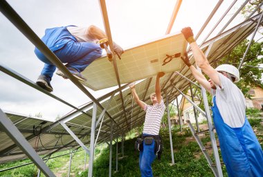 Güneş Fotoğraf volta panel sistem kurulumu. Üç teknisyenler ağır güneş pili yüksek üzerinde kaldırma. Yatırım alternatif enerji, para tasarrufu ve profesyonel inşaat kavramı.