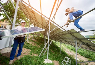 Güneş Fotoğraf volta panel sistem kurulumu. Üç teknisyenler ağır güneş pili yüksek üzerinde kaldırma. Yatırım alternatif enerji, para tasarrufu ve profesyonel inşaat kavramı.