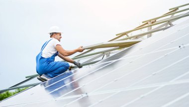 Güneş Fotoğraf volta panel sistem kurulumu. Profesyonel çalışan hard-hat ve genel olarak güneş pili metal üzerinde kaldırma mavi. Alternatif enerji ve profesyonel inşaat kavramı.