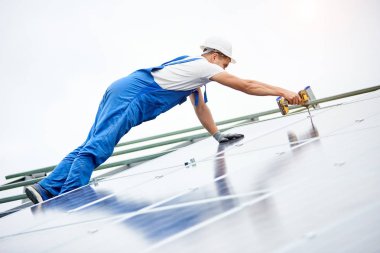 İnşaat işçisi Fotoğraf volta panel güneş sistemi için tornavida kullanarak bağlanır. Profesyonel yükleme ve güneş sistemi, alternatif enerji ve finansal yatırım konsept İnşaat.