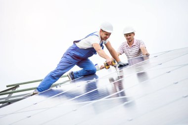 İnşaat işçisi Fotoğraf volta panel güneş sistemi için tornavida kullanarak bağlanır. Profesyonel yükleme ve güneş sistemi, alternatif enerji ve finansal yatırım konsept İnşaat.