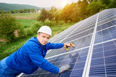 İnşaat işçisi Fotoğraf volta panel güneş sistemi için tornavida kullanarak bağlanır. Profesyonel yükleme ve inşaat Güneş Sistemi'nin, kameraya bakıyor. Alternatif enerji kavramı