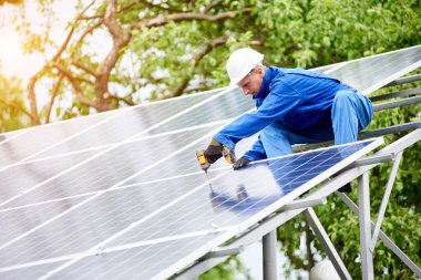 Genç inşaat işçisi Fotoğraf volta panel güneş sistemi parlak güneşli günde tornavida kullanarak bağlanır. Alternatif ucuz güneş enerji üretimi ve karlı finansal yatırım kavramı.