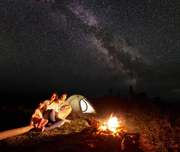 Família Acampar Montanhas Noite Sentado Log Frente Tenda Iluminada Fogueira — Fotografia de Stock