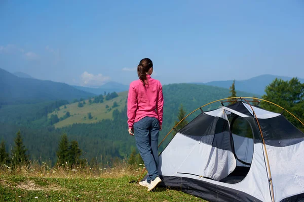 Genç kadın turist turist çadır zevk dağlar parlak yaz sabahı görüntülemek güzel berrak mavi gökyüzünün altında çiçek açan Vadisi üzerinde duran görünümünü arka. Turizm ve seyahat kavramı.