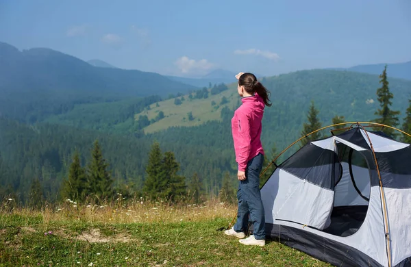 Arkadan görünüm genç uzun saçlı turist kızın çiçek açan valley adlı turistik çadır dağlar manzarayı parlak yaz sabahı güzel berrak mavi gökyüzünün altında tutuyoruz. Turizm ve seyahat kavramı.