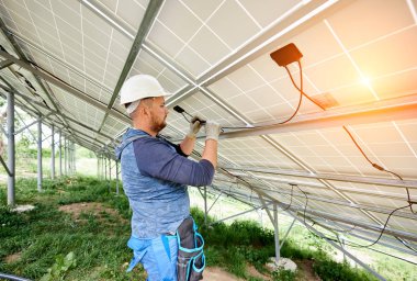 Yükleme ve tek başına güneş Fotoğraf volta panel sistemi kablolama. Yakın çekim Genç elektrikçi elektrik kabloları güneş pilleri içeri hard-hat. Alternatif enerji kavramı.