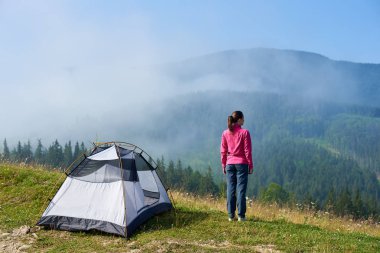 Arkadan görünüşü çiçek açan valley adlı turistik çadır güzel berrak mavi gökyüzünün altında tutuyoruz, sisli dağlar üzerinde yaz sabahı manzarayı genç turist kadın. Turizm ve seyahat kavramı.