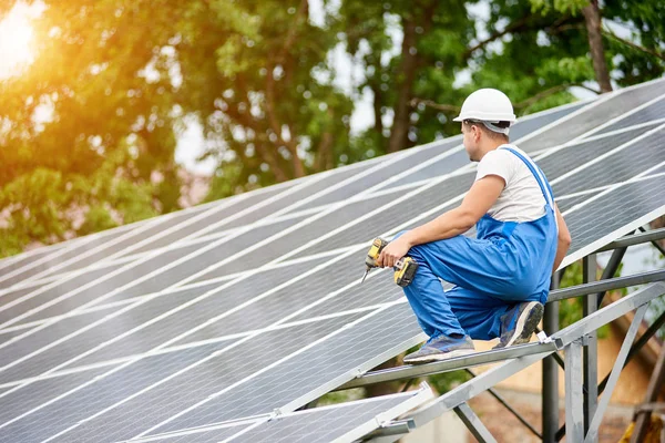 Fotoğraf volta panelleri güneş sistemi parlak yüzey zemin üzerine bağlanan tornavida ile inşaat işçisi. Alternatif enerji, ekoloji koruma ve ucuz elektrik üretim kavramı.