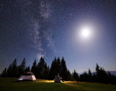 Kamp gece dağ Vadisi. Yalnız turist güzel zevk çadır çimlere oturup..... yıldızlı gökyüzü açık ve parlak ay çam ağaçları içinde aptal. Güzellik, Doğa, turizm ve seyahat kavramı.