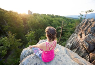 Sabah yeşil ağaçları en fazla orman arka plan üzerinde yoga yaparken büyük kaya üzerine oturan yaz güneş genç ince sportif bir bayan tarafından hava görünümünü yaktı. Spor, jimnastik ve fitness kavramı. Siddhasana