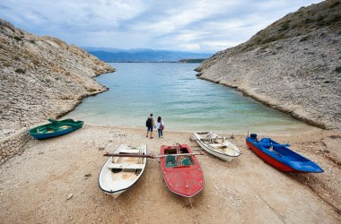 Küçük motorlu tekneler arasında yüksek kayalık sahilleri ve iki genç turistler, erkek ve kadın su kenarında duran el ele tutuşarak sırt çantaları ile rahat liman kıyısında. Balık tutma, Dalış, rekreasyon kavramı Turizm,.