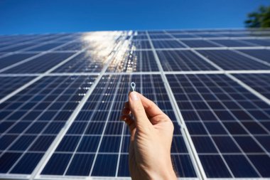 Adam el güneş pili güneş paneli üzerinde arka plan önünde yüklemek için küçük ayrıntı tutmak. 