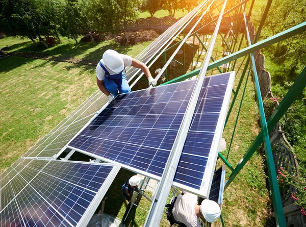 Zespół profesjonalnych monterów instalacji paneli słonecznych na dachu zielonym tuszy. — Zdjęcie stockowe