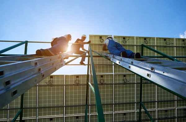Profesyonel işçiler farklı donanımları kullanarak yeşil metal konstrüksiyon üzerinde yükleme güneş panelleri takım. Enerji çözümü için yenilikçi çözüm. Yenilenebilir kaynakları kullanın. Yeşil enerji.