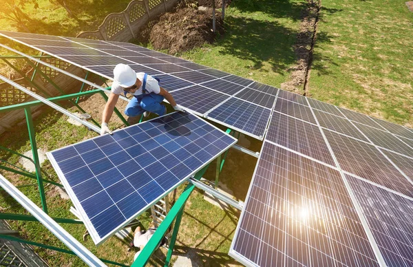 プロ労働者はヘルメットを身に着けている別の機器を使用して緑の金属の構造の太陽電池パネルをインストールします エネルギーを解決するための革新的なソリューションです 再生可能な資源を使用します グリーン エネルギー — ストック写真