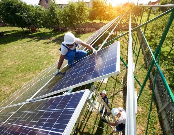 Workers command mounting solar panels on house\'s roof. Innovative high-tech exterior solution. Environment friendly,resources saving, using renewable solar electricity. Warm, sunny weather.